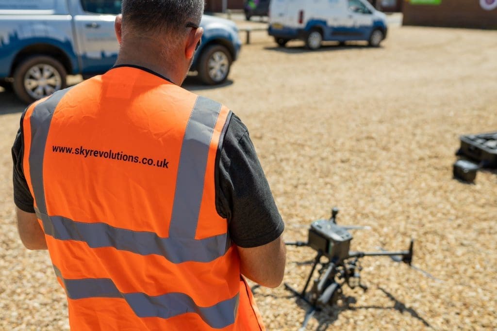 Sky Revolutions team member with drone on ground in the background.