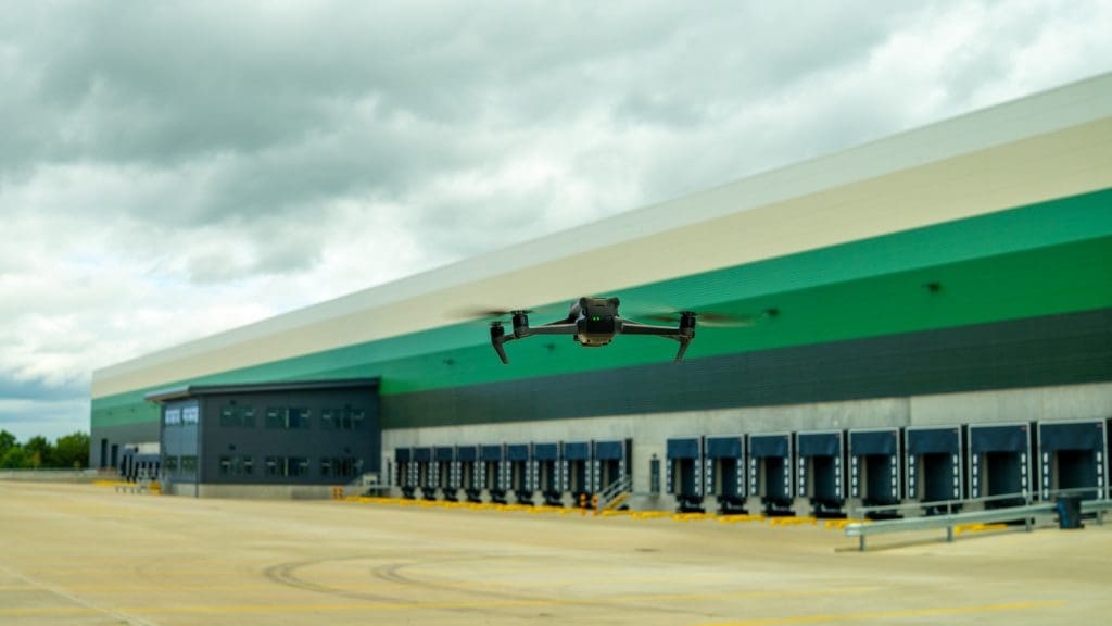 Drone hovering in front of a logistics big box shed.